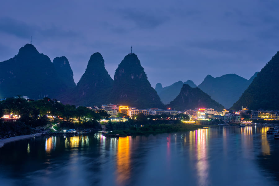 Postal de Yangshuo y su río, con efecto espejo, anocheciendo.